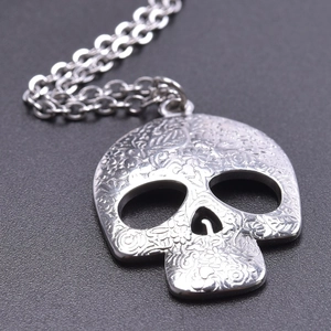 Macro detail of skull pendant showing floral embossed patterns and gothic steel texture