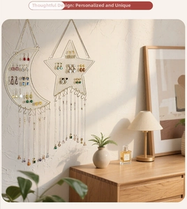 Moon and star shaped wall-mounted metal jewelry organizers with hooks in a cozy home setting