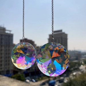 Pair of K9 crystal suncatcher prisms hanging on chains reflecting vibrant rainbow light
