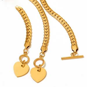 Detail of golden heart pendant on herringbone chain necklace with toggle clasp