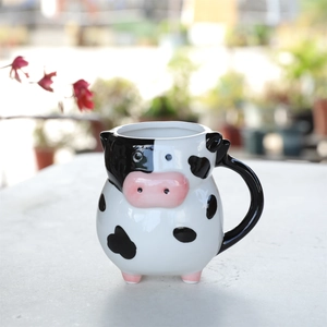 Detail view of the 20oz ceramic cow mug showing 3D spots and pink snout on a white surface