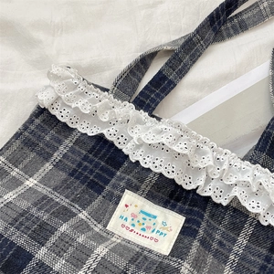 Detail of the cute plaid tote bag showing lace trim and cartoon fabric label