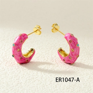 Close-up of pink enamel C-shaped earrings with colorful inset stones and gold plating