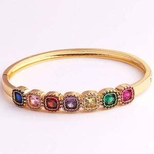 Close-up of gold-plated bangle with multicolor square gemstones and pave-set crystals