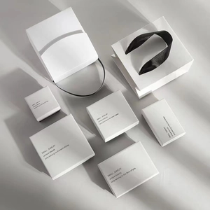 Minimalist white jewelry packaging boxes and gift bags with elegant black ribbon handles