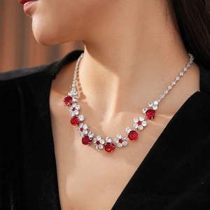 Macro shot of silver zircon flower necklace with red crystals on a female neck
