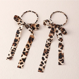 Elegant chiffon leopard print bow earrings with long ribbons on pink background