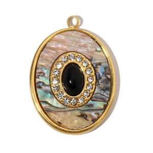 Detailed close-up of oval gold pendant with abalone shell inlay and black center stone