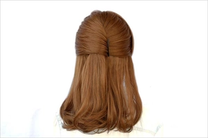 Detail of a black hair styling tool securing a half-up bun on brown hair with white background