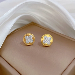 Detailed macro shot of a gold four-leaf clover stud earring with sparkling crystals