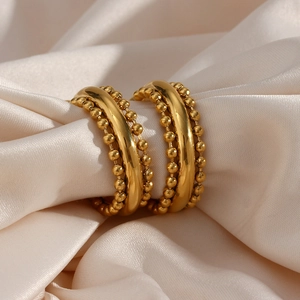 Golden stainless steel hoop earrings with bohemian beaded edges on champagne silk