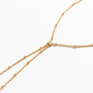 Detail of golden adjustable metal chain bracelet with pearls and rhinestone accents