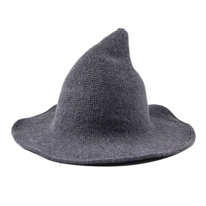 Macro side view of dark grey knitted wizard hat with a high pointed tip and wide brim