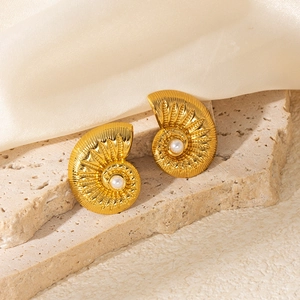 Detail of vintage golden nautilus shell earrings with center white pearl on silk