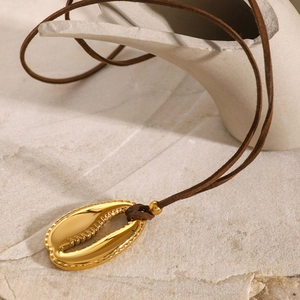 Detail of 18k gold plated shell pendant with dark brown suede cord on stone background