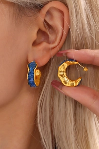 Detailed macro view of PVD gold plated C-shaped earrings with blue crystals on model