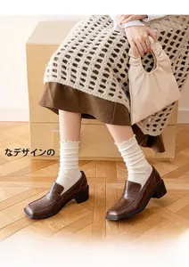 Detail of dark brown leather loafers paired with white ribbed socks for a vintage college style