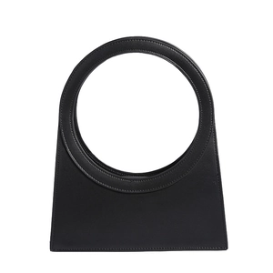 Fashionable black leather handbag with a unique circular hollow handle and trapezoid shape