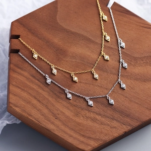 Detailed view of silver and gold necklaces with geometric diamond pendants and rhinestones