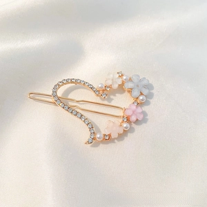 Detailed view of heart-shaped gold hair clip with crystal flowers and pearls