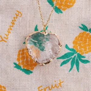 Detailed close-up of faceted heart crystal pendant with gold bezel and twist chain