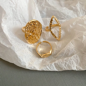 Macro shot of three-piece gold textured ring set featuring oval and rhombus shapes