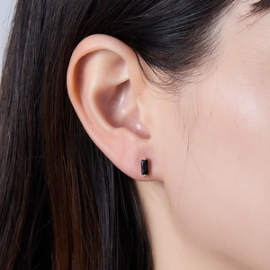 Close-up of elegant gold rectangular black gemstone stud earring worn by a model