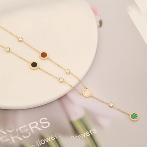 Gold stainless steel necklace with round colorful pendants and crystals on a white plate