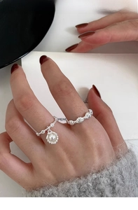 Nahaufnahme der S925 Silbermuschelringe mit Perlenanhängern an einer Hand eines Models