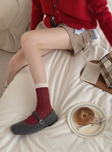 Detail of red knit socks with white lace trim paired with grey Mary Jane shoes
