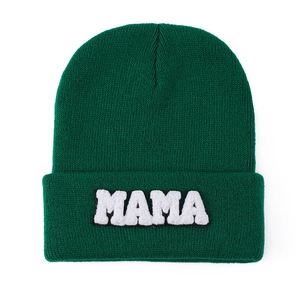 Detailed close-up of dark green knit beanie with white MAMA chenille patch texture