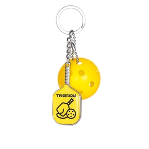 Detailed view of metal pickleball paddle keychain with yellow ball on white backdrop