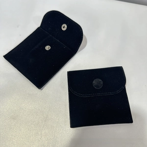 Detail of black velvet jewelry pouches with snap buttons showing open and closed states