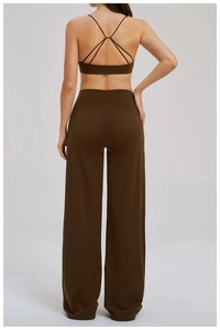 Detail of cross-back yoga bra and high-waisted flared pants in brown performance fabric
