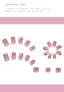 Detail showing gradient pink press-on nails with butterfly charms and glitter accents