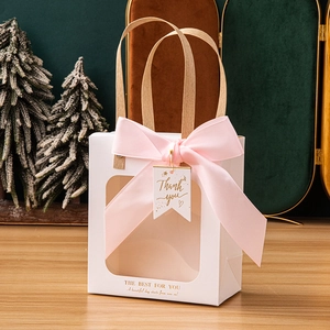 Close-up of a white gift bag with transparent window and large pink silk ribbon bow