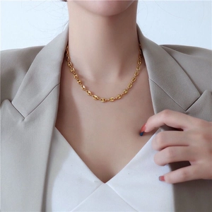 Golden pig nose link necklace worn by a model in a sophisticated grey blazer