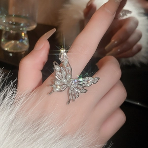 Detail of a butterfly ring with pearls and zircons on a model's hand with fur sleeve