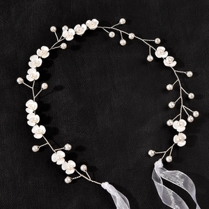 Detail of bridal headband featuring white flowers, pearls and flexible silver wire ties