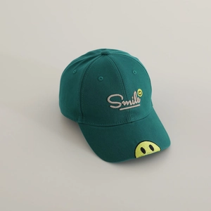 Detail of smile embroidery and textured cotton fabric on dark green kids baseball cap