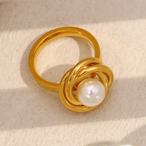Gros plan sur une bague spirale plaquée or 18 carats ornée d'une perle blanche