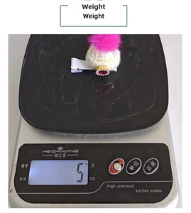 Detail view of a mini Christmas knitted hat hair clip weighing 5g on a digital scale