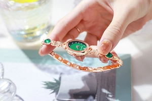 Detailed view of luxury rose gold bracelet watch with emerald green dial and crystals