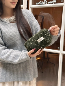 Gros plan d'une trousse à crayons vert foncé en peluche avec une texture douce de laine