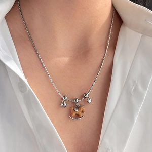 Chic silver snake chain necklace with wooden horse and heart pendant on a model neck