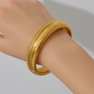 Vista macro de la pulsera ancha tubogas de acero dorado con textura de rayas pulidas