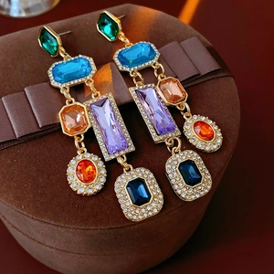 Details von Vintage-Goldohrringen mit bunten Edelsteinen auf brauner Geschenkbox