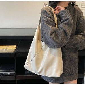 Detail of cream hobo shoulder bag featuring silver metal studs on smooth faux leather