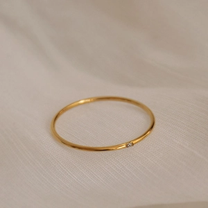 Nahaufnahme eines minimalistischen dünnen Goldrings mit einem kleinen Zirkonia-Stein