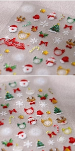 Makro-Detail von 3D-geprägten Weihnachts-Nagelstickern mit Weihnachtsmann und Rentier-Motiven
